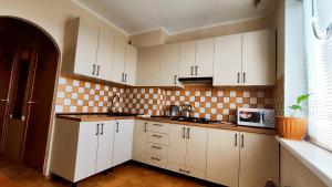 a kitchen with white cabinets and a tile wall at Василя Стуса 10 City Rooms in Bila Tserkva