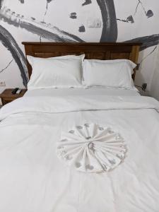 a white bed with a flower decoration on it at HOTEL MAA MEVFOU Hmm in Yaoundé