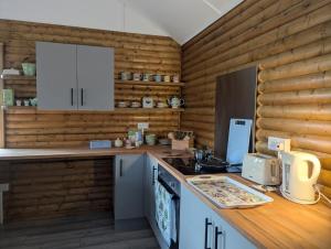 a kitchen with white cabinets and a wooden wall at The Lodge at Tetley in Crowle