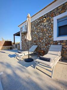 a patio with two lounge chairs and an umbrella at Mandilaria stone house in Afantou
