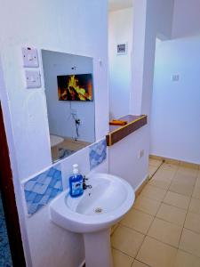 Un baño con lavabo y fuego en el espejo. en Rock Homes, en Mombasa