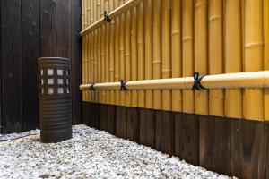 ein gelber Zaun mit einem schwarzen Pfosten neben Kies in der Unterkunft Family-Friendly, 2-Story Kyoto House, Walk to Gion in Kyoto + 17 Fotos