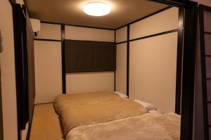 ein Schlafzimmer mit zwei Betten und einer Wandleuchte in der Unterkunft Family-Friendly, 2-Story Kyoto House, Walk to Gion in Kyoto