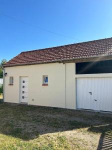 a garage with white doors and a brown roof at Logement : 2 chambres (5 couchages), salle de bain in Pierrefitte-sur-Sauldre