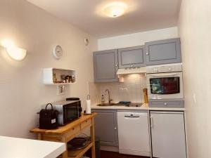 a small kitchen with white cabinets and a microwave at Opale Sun Hardelot in Neufchâtel-Hardelot