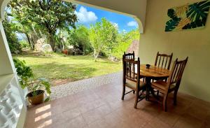 a dining room with a table and chairs and a window at Jardin Marron in Baie Sainte Anne