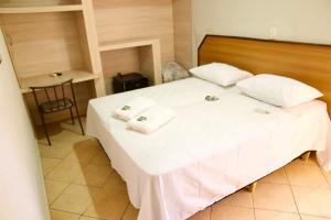 a bedroom with a large white bed with towels on it at Vivenda Del Sol in Bauru