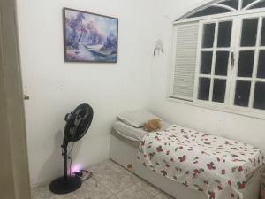a bedroom with a fan next to a bed and a window at Casa para alugar em Salvador in Salvador