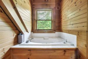 a bath tub in a wooden bathroom with a window at Your Getaway Oasis in Sevierville +24 photos