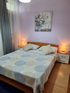 a bedroom with a bed and two lamps and a painting at Apartments Gržanov in Sutomišćica