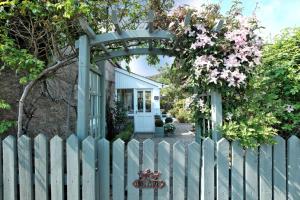 a white fence with a gate and a fence with flowers at Craigen Cottage Ballater in Ballater