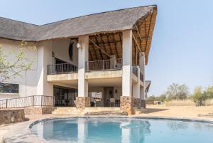 a house with a large pool in front of it at Zebula Golf Estate & Spa Executive Holiday Homes in Mabula