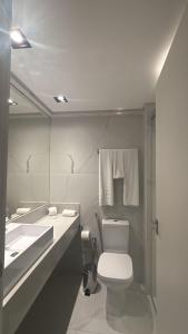 a bathroom with a toilet and a sink and a mirror at Apartamento TOP - No Praia Brava Hotel in Florianópolis