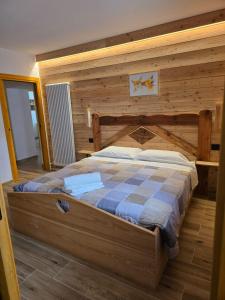 a bedroom with a bed with a wooden wall at La casa di Nil - Appartamento Volpe in Spiazzo