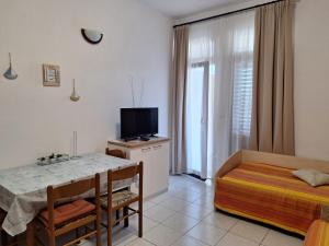 a room with a table and a bed and a television at Apartments Gržanov in Sutomišćica