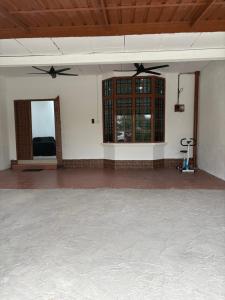a large room with a ceiling fan and windows at Bidor Homestay in Bidur