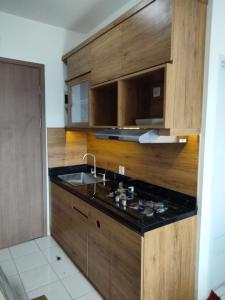 eine Küche mit Holzschränken, einer Spüle und einer Theke in der Unterkunft Dahoma lantai 6 in Tjikuda Tiga