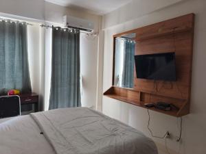 Schlafzimmer mit einem Bett und einem TV an der Wand in der Unterkunft Dahoma lantai 6 in Tjikuda Tiga