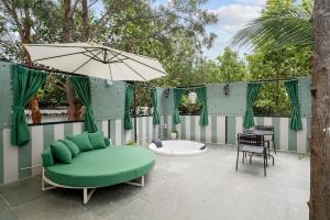 a green couch and an umbrella on a patio at Bangalore Hideaway 1BHK Spanish villa Casa Rio in Denkanikota