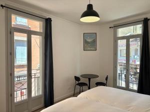 a bedroom with a bed and a table and windows at Lourdes Backpackers in Lourdes