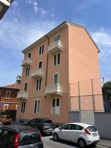 a pink building with cars parked in front of it at Casa Marelli in Sesto San Giovanni
