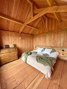 a bedroom with a bed in a wooden cabin at Le Refuge en bois nuit insolite en pleine Nature in Glanville