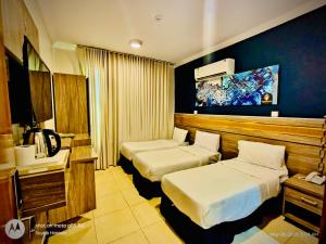 a hotel room with two beds and a tv at Hotel Chatha Manoura- in Medina