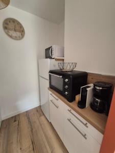 a small kitchen with a microwave and a refrigerator at Charmant studio avec cour privée in Rochefort +1 photo