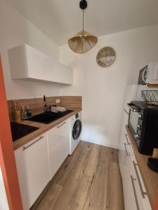 a kitchen with white cabinets and a sink and a microwave at Charmant studio avec cour privée in Rochefort