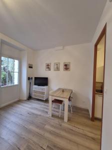 a living room with a table and a television at Charmant studio avec cour privée in Rochefort