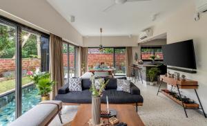 a living room with a couch and a tv at Villa Reverie By AT Villas in Vagator