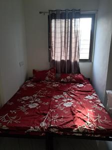Bett mit einer roten Bettdecke vor einem Fenster in der Unterkunft Arsh Mahal in Pune