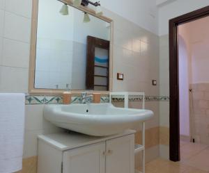 ein Badezimmer mit einem weißen Waschbecken und einem Spiegel in der Unterkunft Villa dei Tigli - trulli e relax in Castellana Grotte + 40 Fotos