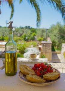ein Teller mit Brot und Tomaten und eine Flasche Öl in der Unterkunft Villa dei Tigli - trulli e relax in Castellana Grotte
