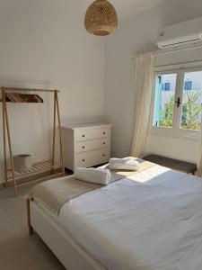 a white bedroom with a bed and a window at Anemelia by the Sea - Lipsi in Lipsoi