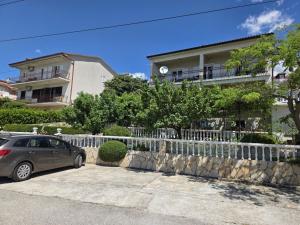une voiture garée à côté d'une clôture devant un bâtiment dans l'établissement LEO ROOM 2 NV - Room for 2-3 persons with bathroom, balcony (no kitchen), à Novi Vinodolski