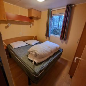 a bed in a small room with a window at Mobile home 5 pers en campagne Proche Puy du fou 110CB in La Boissière-de-Montaigu +2 photos
