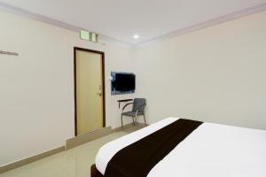 ハイデラバードにあるHotel O Madhu Grand Luxury Roomsのベッドと椅子とテレビのある寝室