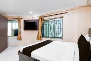 コルカタにあるHotel O AK International Hotelのベッドとテレビと窓のある寝室