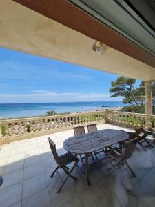 a table and chairs on a patio with a view of the ocean at Appartement Les pieds dans l eau in Hyères