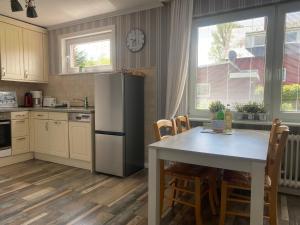 a kitchen with a table and a refrigerator at Haus Carstensen-Bungalow 2 in Wyk auf Föhr +11 photos