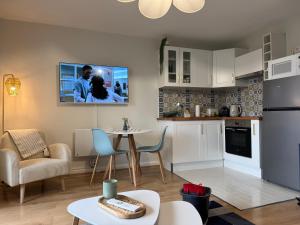 a living room with a kitchen with a tv on the wall at Le Bleu Marine, grand studio au calme, à 2 pas du lac ! in Gérardmer