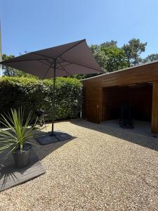 a patio with an umbrella next to a building at L'étoile des pins in Longeville-sur-Mer