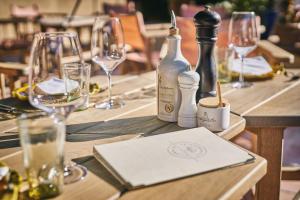 a wooden table with wine glasses and bottles on it at La Ferme D'Augustin in Saint-Tropez