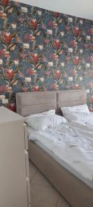 Bett in einem Schlafzimmer mit Blumentapete in der Unterkunft Don Simon Apartment in Durrës