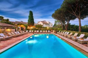 a pool with lounge chairs and a house in the background at La Ferme D'Augustin in Saint-Tropez