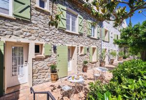 a stone house with a table and chairs outside at La Ferme D'Augustin in Saint-Tropez