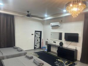 a room with two beds and a flat screen tv at Umaira Roomstay Arau in Arau +3 photos