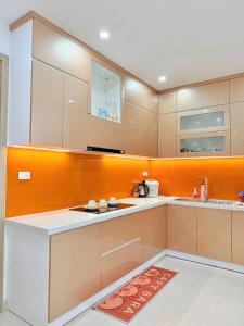 - une cuisine avec des placards blancs et un mur orange dans l'établissement Sky Homestay Huế, à Thôn Văn Dương