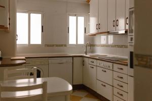 a kitchen with white cabinets and a sink and a table at Albaceteloft Avenida España in Albacete